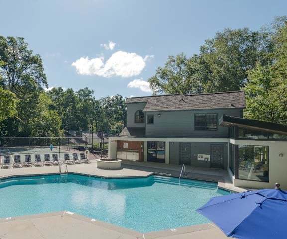 A large swimming pool surrounded by trees and a building in the background.