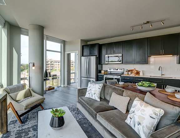 a living room and kitchen with dark cabinets and a large window