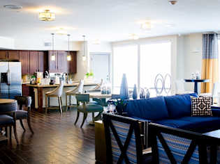 A living room with a blue couch and a dining table with chairs.