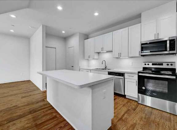 A modern kitchen with stainless steel appliances and wooden floors.
