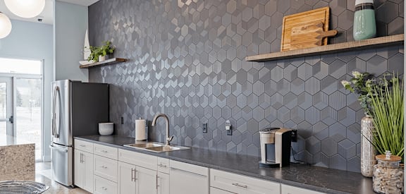 A kitchen with a grey backsplash and white cabinets.