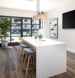 a kitchen with a long white counter top and a bar with stools at La Jolla Blue, San Diego, California