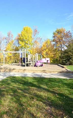 A park with a playground and trees in autumn colors.