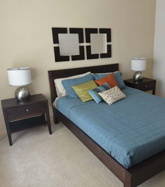 A bed with a blue comforter and two nightstands with lamps.