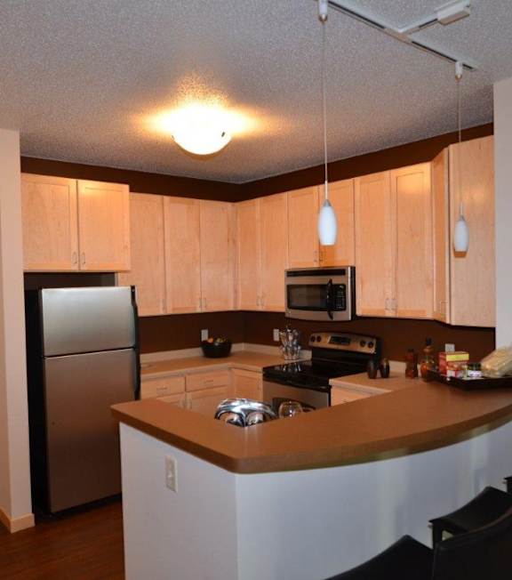 A kitchen with a refrigerator, microwave, and oven.