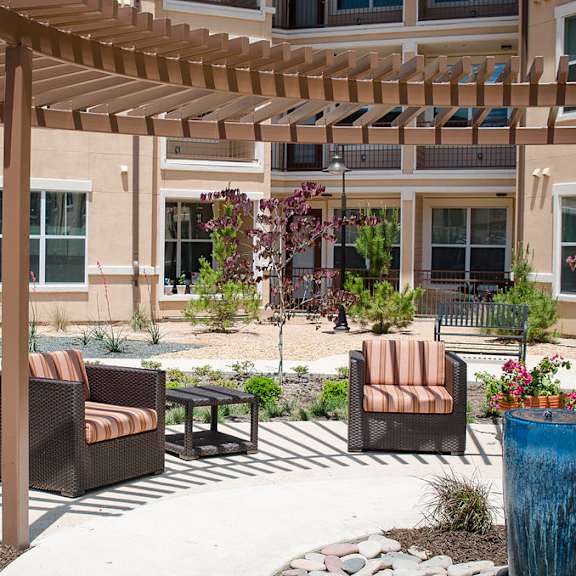 A patio with a wooden pergola and wicker chairs.