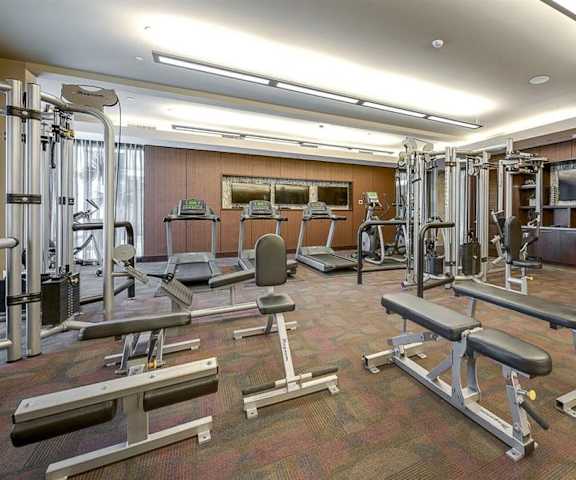 A gym with cardio machines, TVs, and weight machines at Cityplace Heights. 
