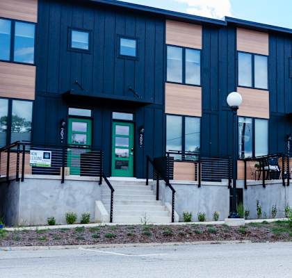 A modern building with a black and brown facade and a green door.
