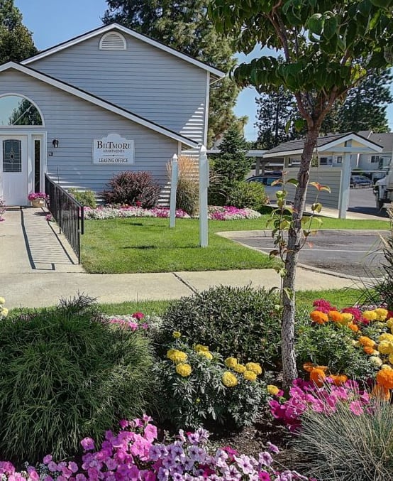 a flower garden in front of a row of houses