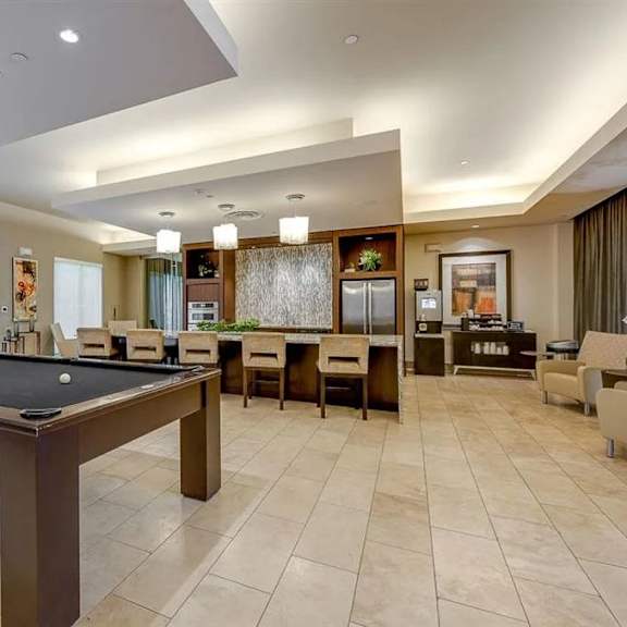 The resident lounge and gaming room with a pool table, counter and bar stools, chairs, a kitchen, and a coffee station at Cityplace Heights. 