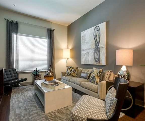 The living room with a couch, coffee table, decorations, a TV, and balcony at Cityplace Heights. 