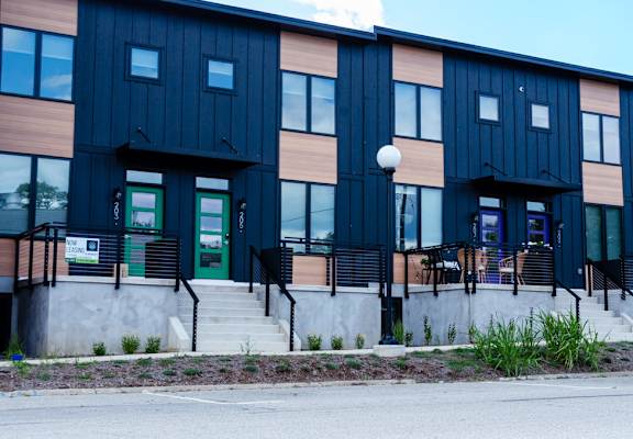 A modern building with a black and brown facade and a green door.