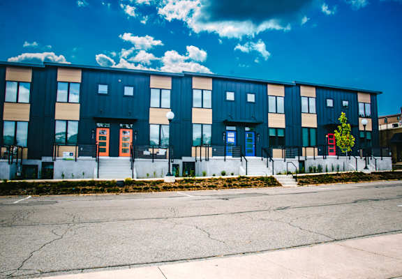 A row of modern townhouses with a clear blue sky above.