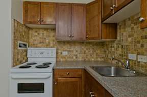 A kitchen with a white stove and wooden cabinets.