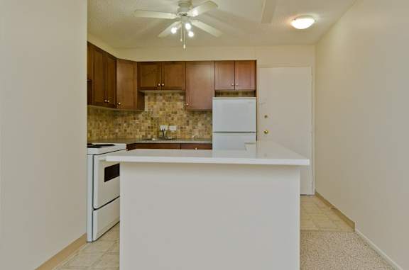 A kitchen with a white island and a white refrigerator.