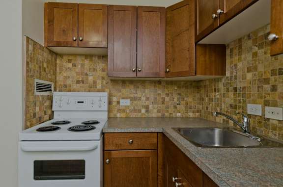 A kitchen with a white stove and wooden cabinets.