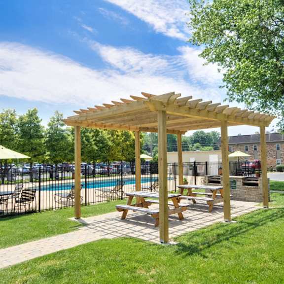 a picnic area with a pergola next to a swimming pool