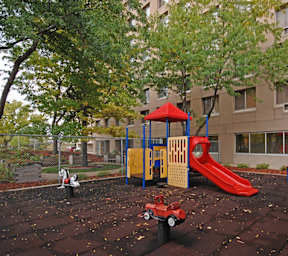 A playground with a red slide and a yellow and blue playhouse.
