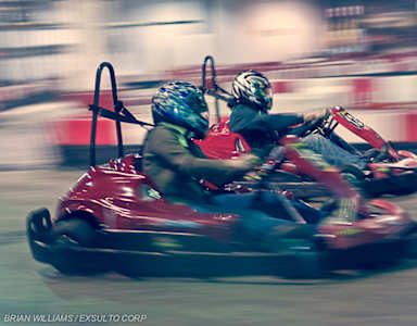 Two people are riding go-karts on a track.
