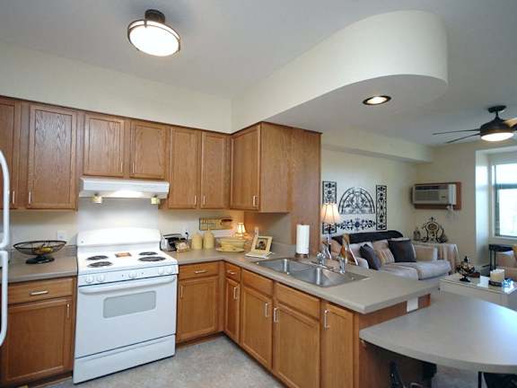 A kitchen with wooden cabinets and a white stove top oven.