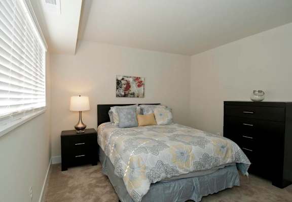 A bedroom with a bed, nightstand, and a lamp.