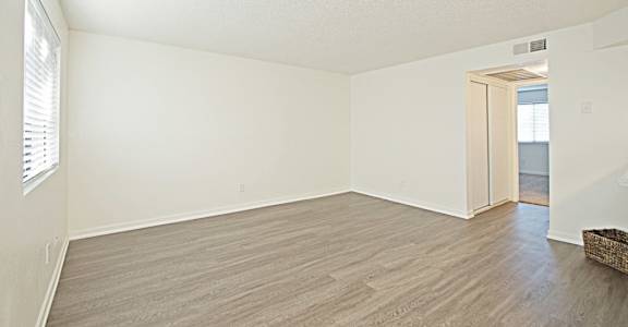 an empty living room with wood flooring and white walls