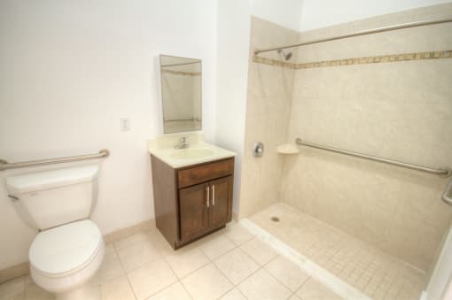 Bathroom with white tiles, wooden cabinet and handicap shower