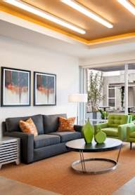 A living room with a black couch, green chairs, and a coffee table.