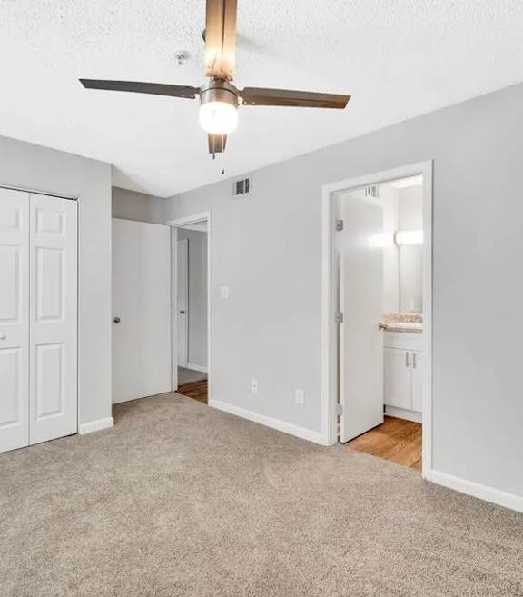 A room with a ceiling fan and carpeted floor.