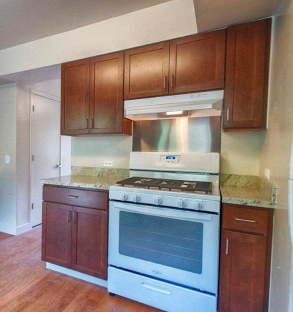 A kitchen with wooden cabinets and a white stove top oven.