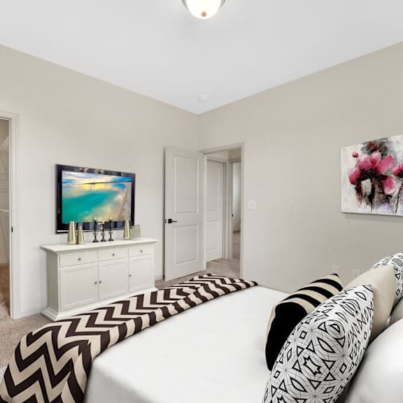 A living room with a white couch and a television on a white cabinet.