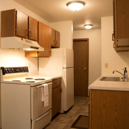 a kitchen with a stove refrigerator and a sink. Fargo, ND Candlelight Apartments
