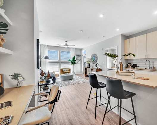 an open kitchen and living room with a bar and stools