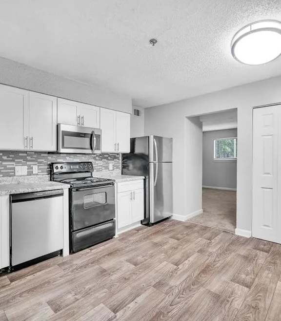 A kitchen with white cabinets and wooden floors.