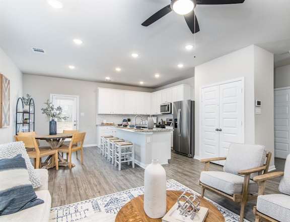 a living room and kitchen area with a ceiling fan