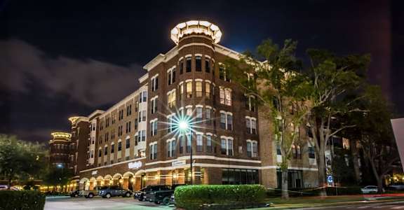 A large, well-lit building with a curved corner and a lit-up sign on the front.