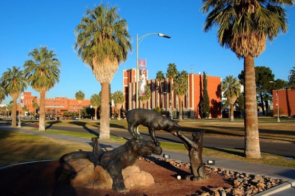 a statue of a cow and a bull in a park with palm trees