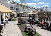Thumbnail 4 of 5 - a patio with chairs and umbrellas in front of a house
