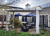 Thumbnail 1 of 3 - a patio with tables and umbrellas in front of a house