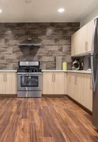 A kitchen with wooden floors and a stainless steel refrigerator.