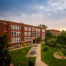 A large red brick building with a green lawn in front.