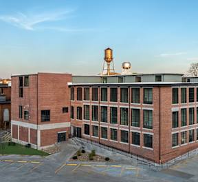 A large red brick building with a parking lot in front.