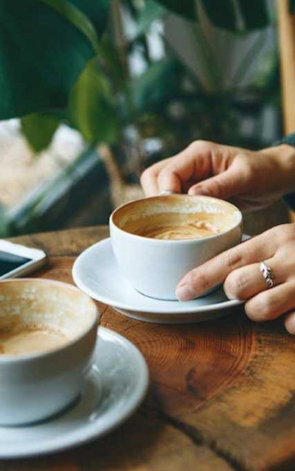 A person is pouring a beverage into a cup on a wooden table.