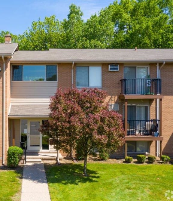 the outlook of an apartment building with green grass and trees
