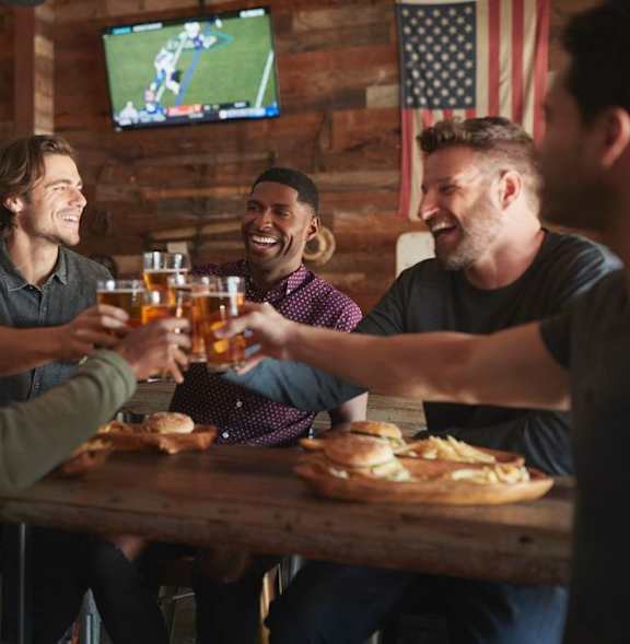 A group of people toasting with beer glasses in a bar.