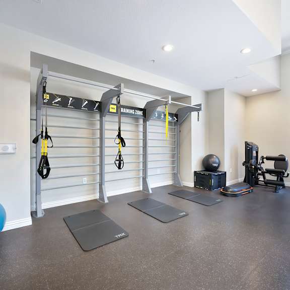 A gym with a blue exercise ball, a black punching bag, and a weight machine.