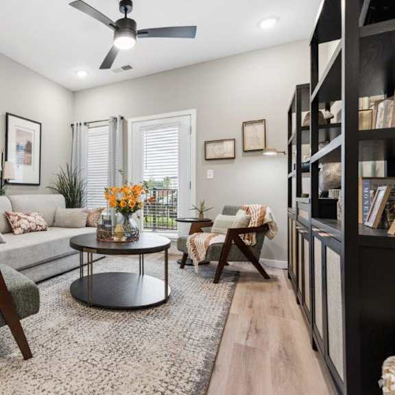 A living room with a ceiling fan, a couch, a coffee table, and a television.