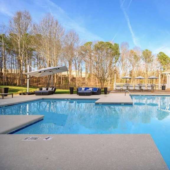 A large swimming pool with a deck and sun loungers.