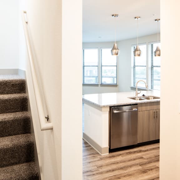 A staircase leads to a kitchen area with a sink and cabinets.