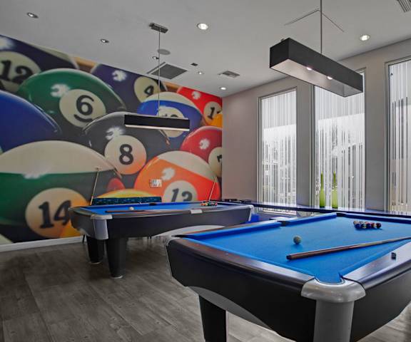 A games room with two pool tables and a large mural of billiards balls at Aspire at Pinnacle Peak. 